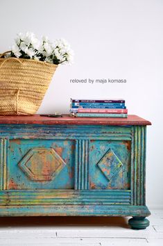 an old dresser has flowers in a basket on it and books are sitting on top