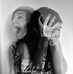 a black and white photo of a person covering their face with his hands while screaming