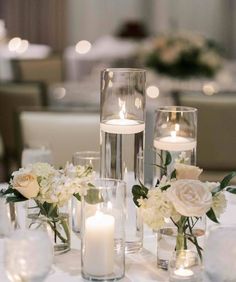 the centerpieces on this table are filled with flowers and candles, along with clear glass vases