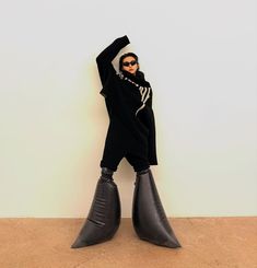 a woman in black and white is standing with her legs up on the ground wearing large black boots