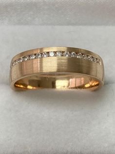 a yellow gold wedding ring with diamonds on it's side, sitting on a white cloth