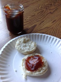 two biscuits with jam on them sit on a plate next to a jar of jelly