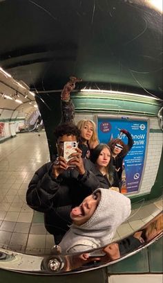 a group of people taking pictures with their cell phones in a mirror at the subway station