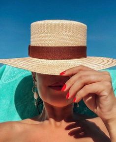 a woman with red nails wearing a straw hat