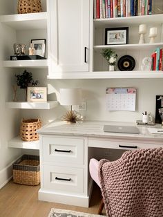 a home office with white cabinets and shelves