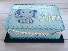 a blue and white baby shower cake with an elephant on it's side that says congratulations stephanie