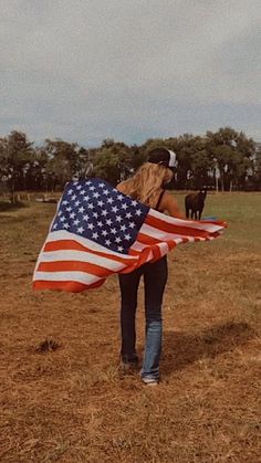 a woman holding an american flag in a field