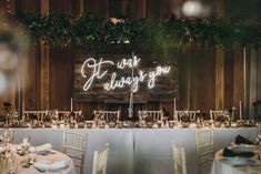 a long table is set up with white linens and place settings for an event