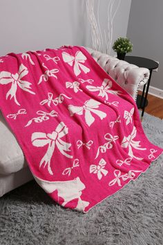 a pink and white blanket sitting on top of a couch