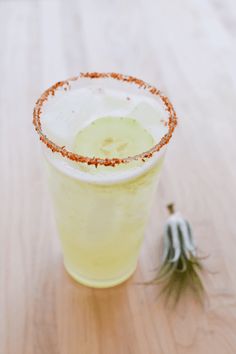 a drink sitting on top of a wooden table next to an orange peel and green pepper