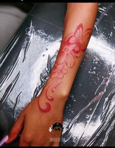 a woman's arm with a red butterfly tattoo on the left side of her arm