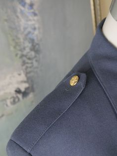 This European vintage air force military jacket has a notch collar and padded shoulders, and closes in the front with four gold buttons with a wings and crown crest. The blazer features buttoned epaulets and four buttoned patch pockets on the front, and each sleeve has a darker blue band with gold embroidered wings and crown near the cuff. A Nederland patch is attached to the left upper sleeve. The blazer is fully lined in blue satin viscose fabric. Chest = 46 inches (116.84cm)(the extra 2 inche Classic Button-up Outerwear With Gold Buttons, Classic Outerwear With Gold Buttons, Military Style Outerwear With Epaulettes For Work, Military Outerwear With Epaulettes For Work, Military Style Blazer With Lapel Collar And Button Closure, Military Long Sleeve Blazer With Button Closure, Classic Formal Outerwear With Epaulettes, Military Style Double-breasted Blazer, Military Style Blazer With Button Closure