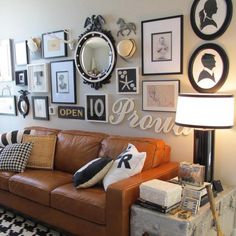 a living room filled with furniture and lots of framed pictures on the wall above it