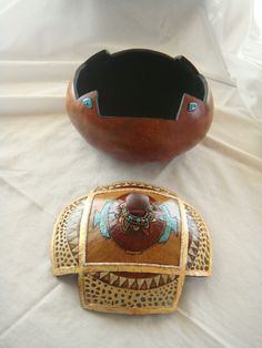 two wooden bowls sitting next to each other on a white tablecloth covered surface, with one bowl in the shape of an elephant's head