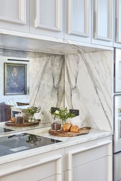 a kitchen with marble counter tops and white cabinets, along with croissants