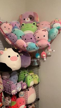 a bunch of stuffed animals are hanging on the wall above a shelf in a room