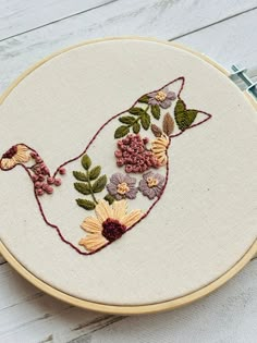 a close up of a embroidery on a white surface with flowers and leaves in it