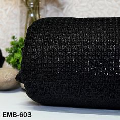 a black sequined purse sitting on top of a table next to a vase