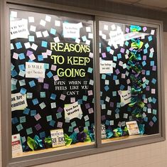 a bulletin board with sticky notes attached to the front of it in a school hallway