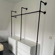 a bedroom with two white dressers and three black rails on the wall above them