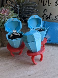 two blue and red vases sitting on top of a table next to a potted plant