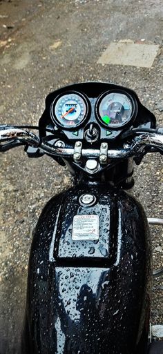 the handlebars and gauges on a motorcycle are covered in raindrops