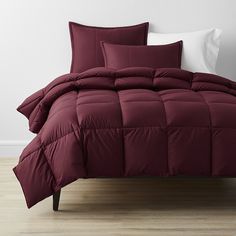 a bed with red comforter and pillows on it