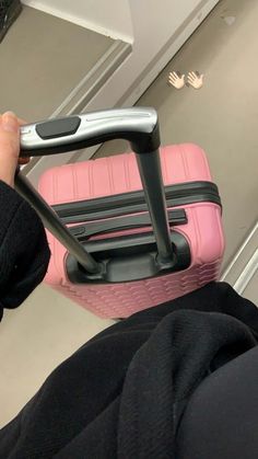 a person holding a pink piece of luggage in their left hand, with the handle extended