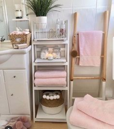 a white bathroom with pink towels on the shelf and other items in front of it