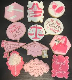 decorated cookies are arranged on a table with pink and white frosting, including one for law school