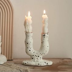 two white candles sitting on top of a wooden table