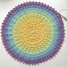 a crocheted rainbow doily with yarn and scissors