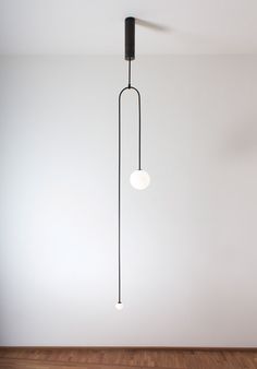 a black and white light hanging from a ceiling in a room with wood flooring