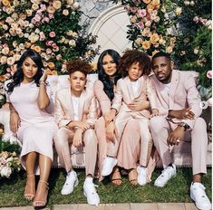 a group of people sitting next to each other in front of a flower covered wall