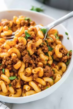 a white bowl filled with macaroni and cheese on top of a marble counter