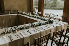 the table is set up with place settings and greenery on it for an elegant wedding reception