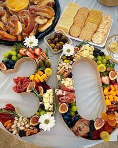 a number made out of fruits and nuts on top of a white table cloth covered with food