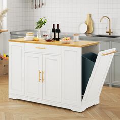 a kitchen island with wine bottles and glasses on it in the middle of a wooden floor