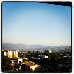 a view of the city with mountains in the backgrouund and blue sky