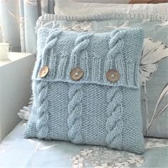 a blue knitted pillow sitting on top of a bed