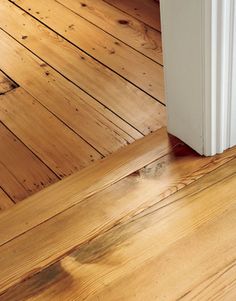 a white refrigerator sitting on top of a wooden floor next to a door and window