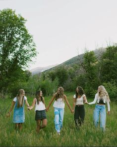 four girls holding hands and walking through tall grass