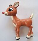 a toy deer is standing on a white surface