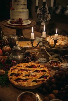 a table topped with pies and candles next to other foods on top of it