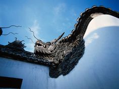 a dragon sculpture on the side of a building with blue skies in the back ground