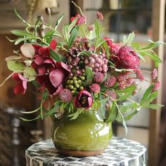 a green vase filled with flowers on top of a table