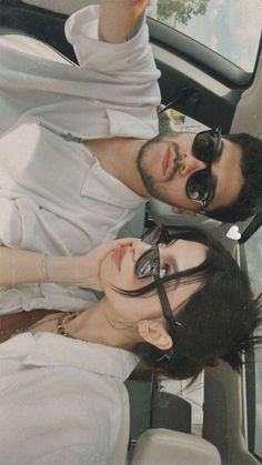 two people sitting in the back seat of a car, one with sunglasses on his head