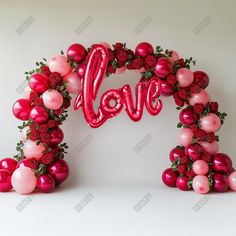 an arch made out of balloons with the word love spelled in red and pink letters