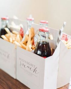 two bottles of soda and french fries in a white box on a wooden table top