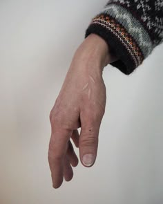 a person's hand with a small tattoo on the left side of their arm